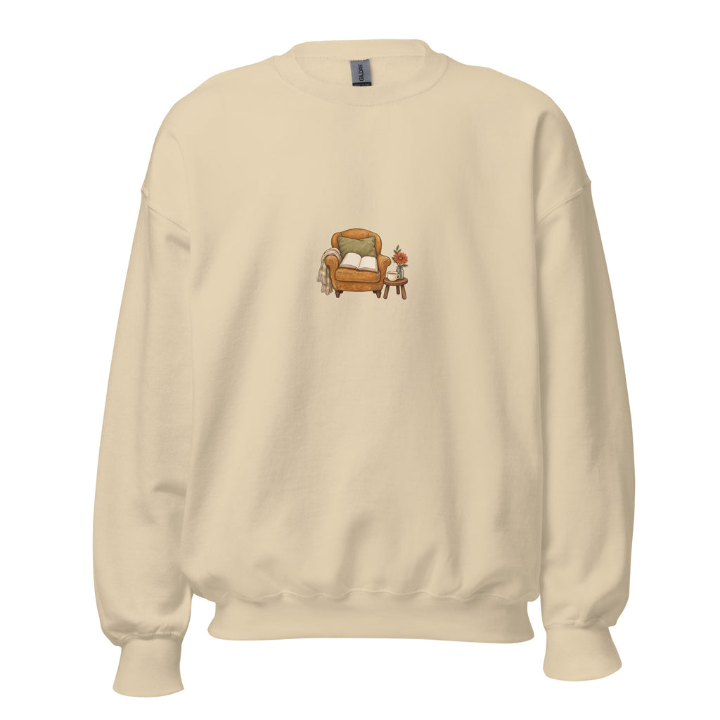Product mockup of Cozy Reading Chair unisex sweatshirt in Sand, front view with armchair, open book and side table